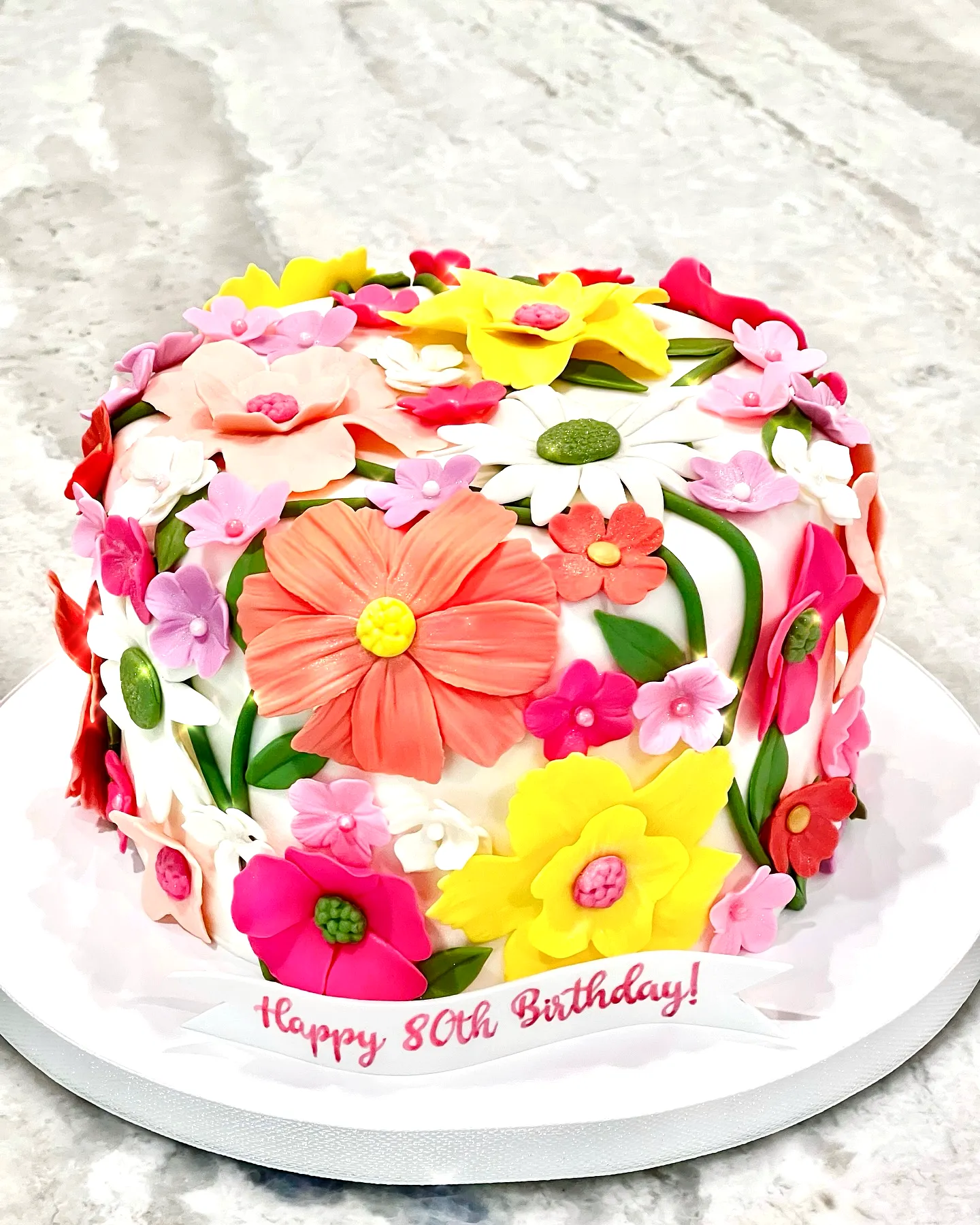 Adorable 80th Birthday Cake with Vibrant Floral Decorations and White Icing