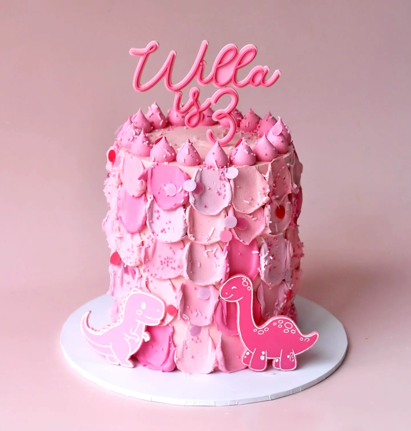 Adorable dinosaur birthday cake design with playful pink ombre frosting