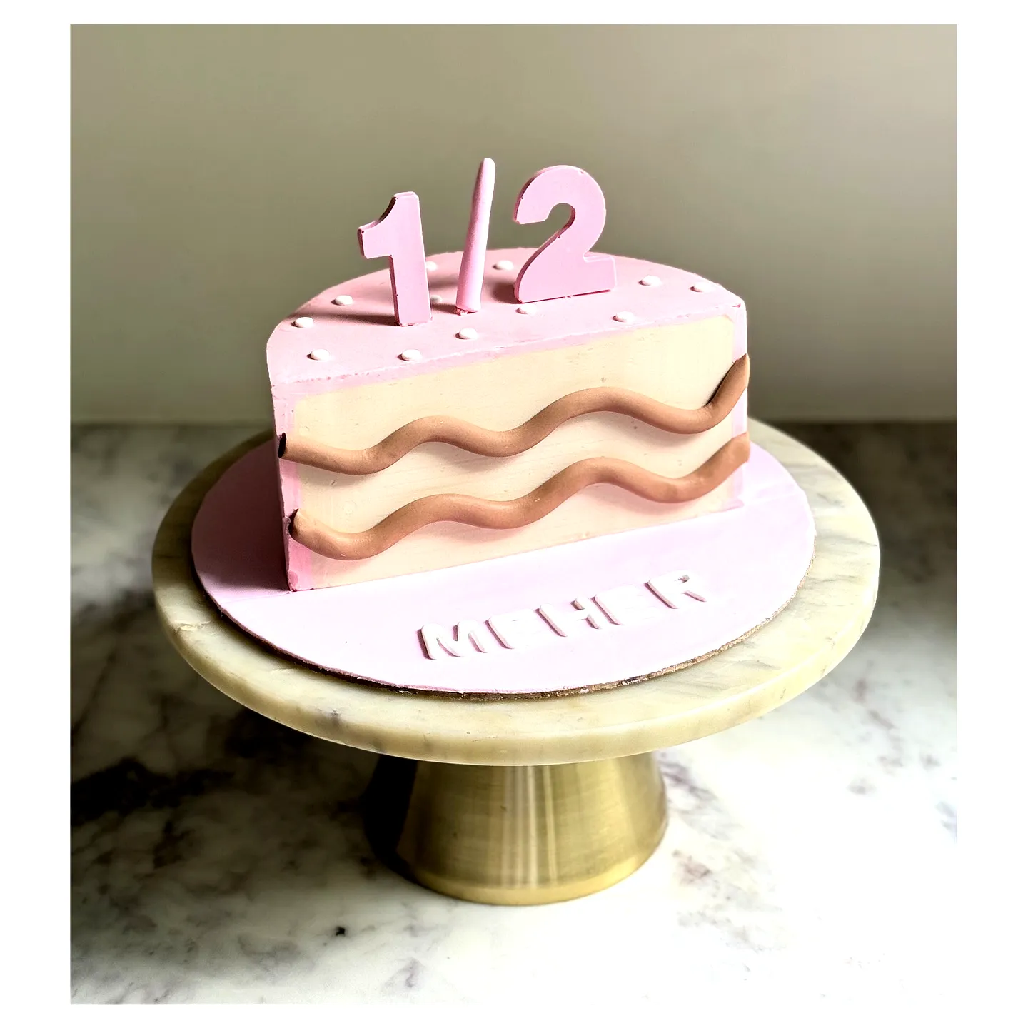 Adorable half birthday cake in soft pink with playful chocolate layers
