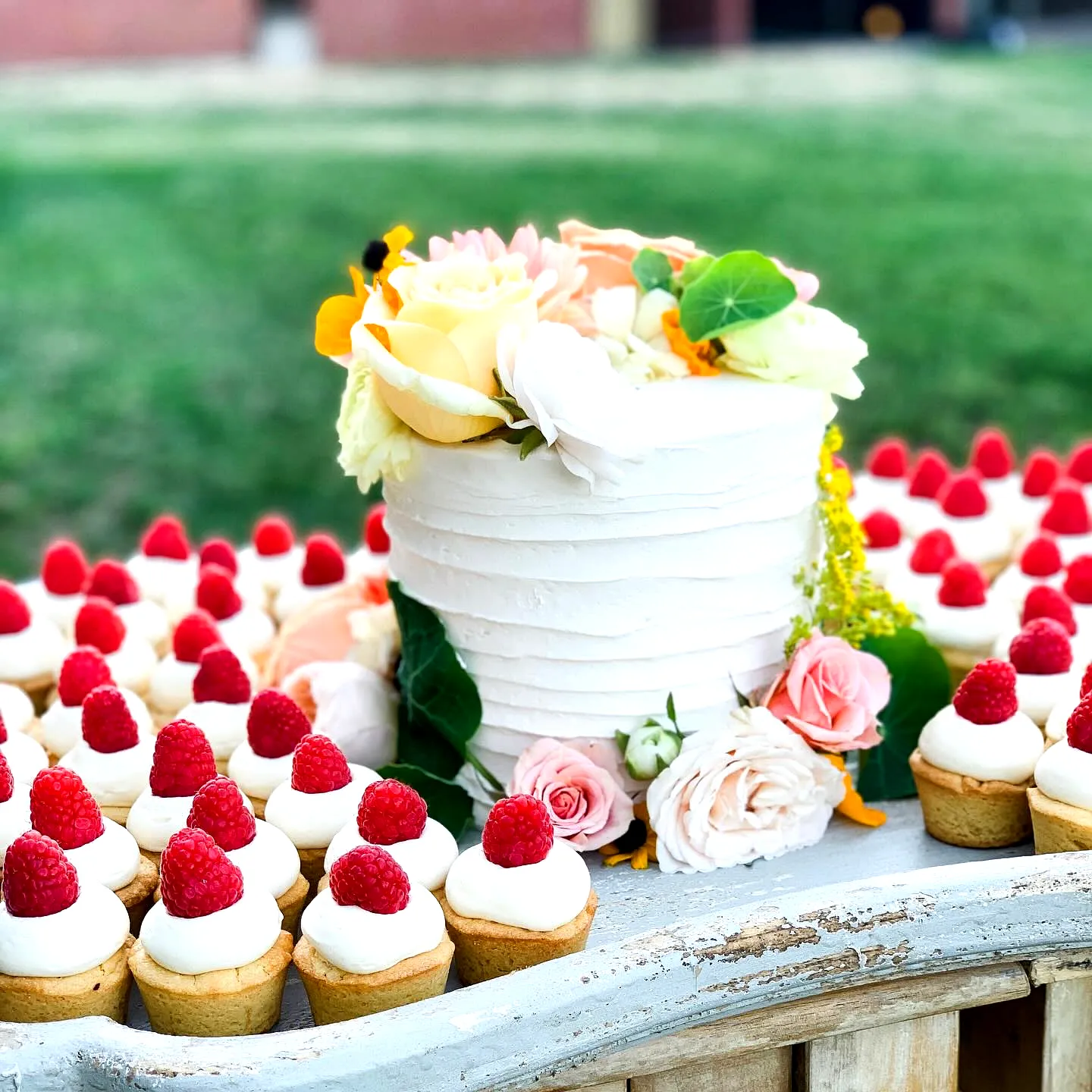 Charming Summer Wedding Cake with Fresh Flowers and Vibrant Cupcakes