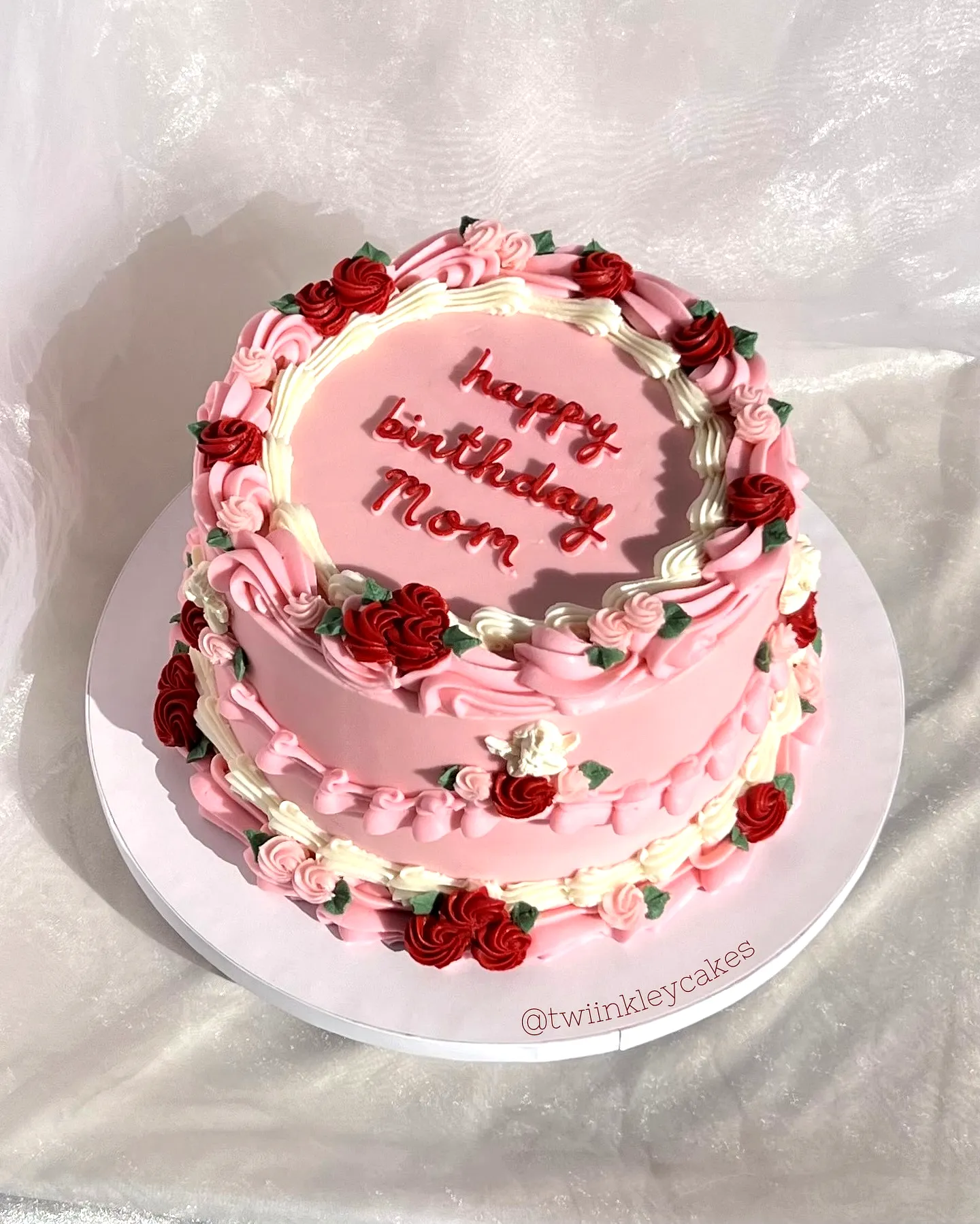 Charming two-tiered birthday cake for women adorned with roses and pink buttercream