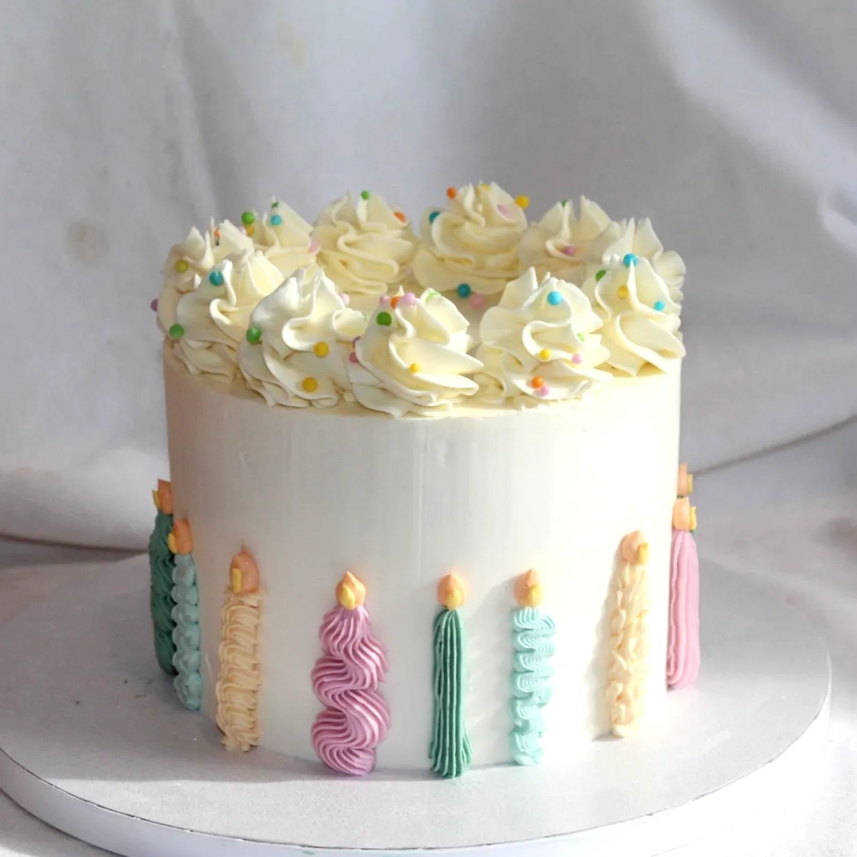 Charming White Birthday Cake with Festive Buttercream and Adorable Candles