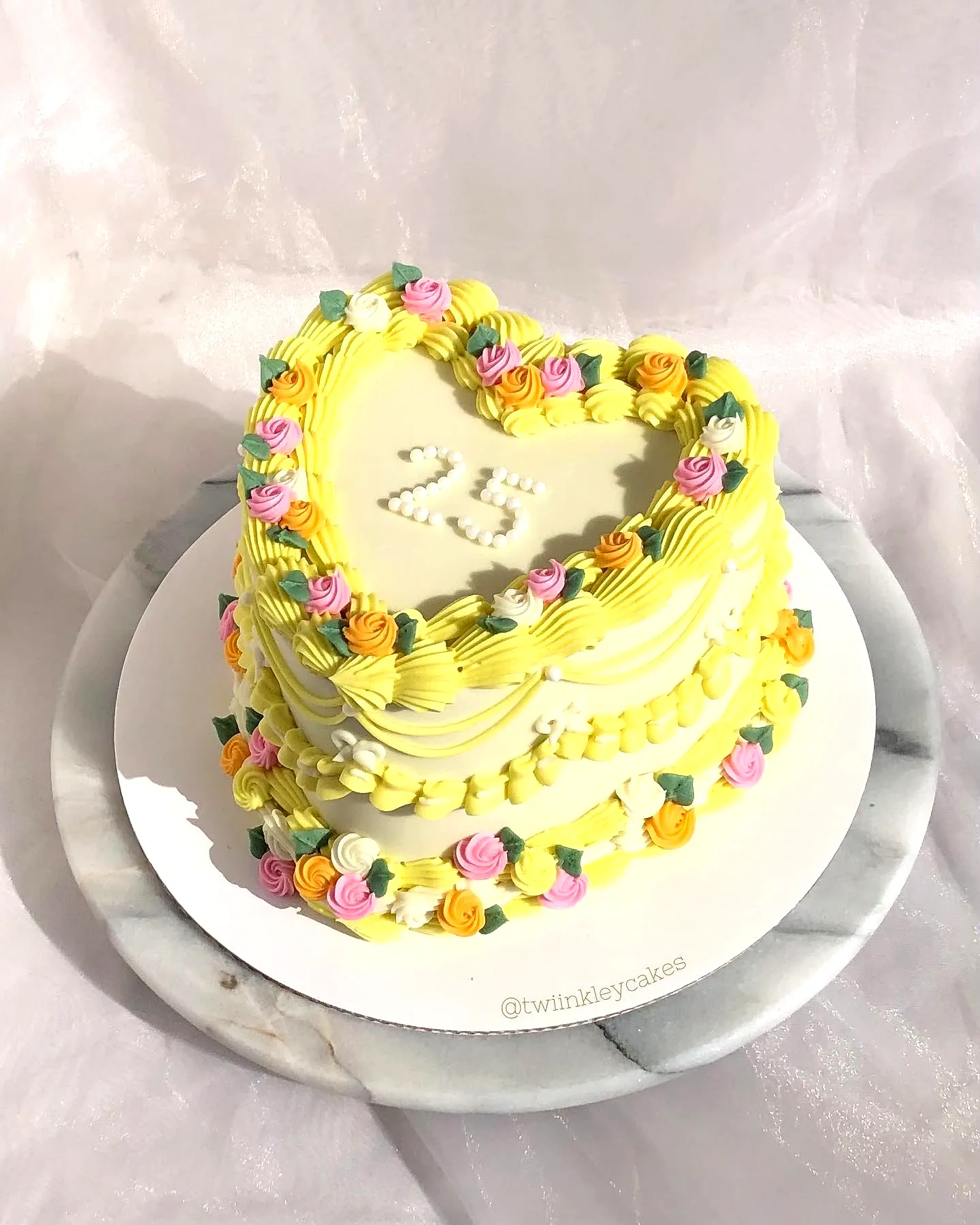 Charming yellow birthday cake design with pastel roses and heart shape