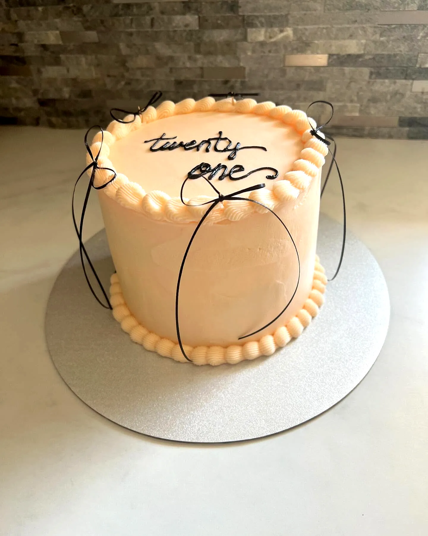 Chic peach 21st birthday cake with elegant black accents and smooth frosting