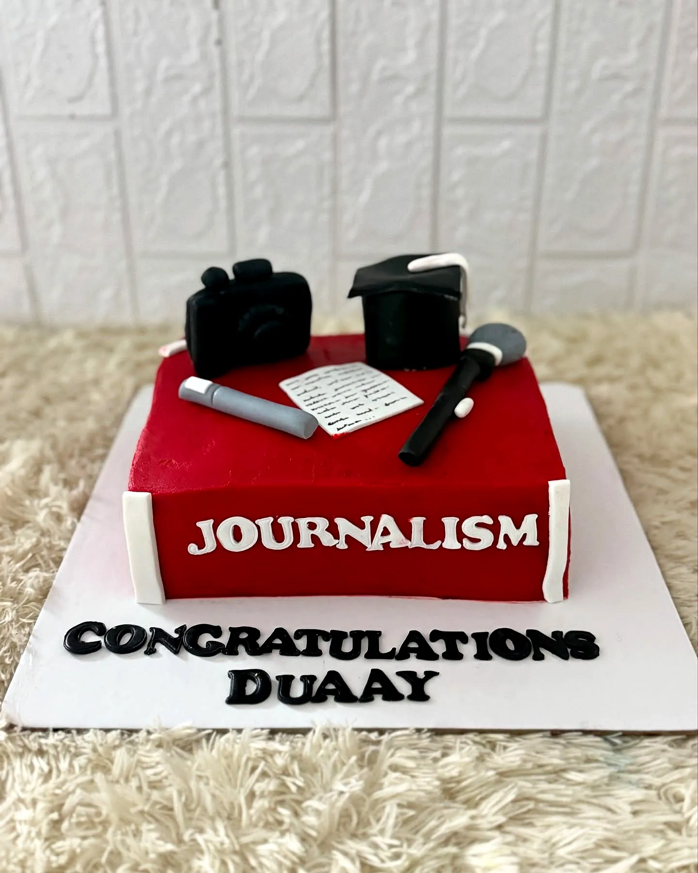 Creative red and black graduation cake design for journalism celebration