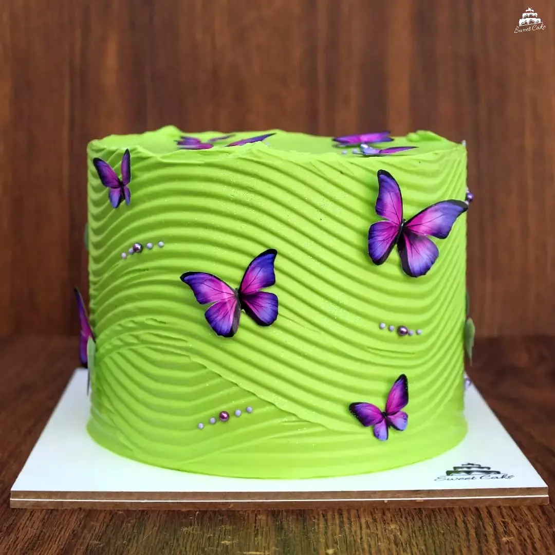Cute green birthday cake with vibrant buttercream and whimsical butterfly decor