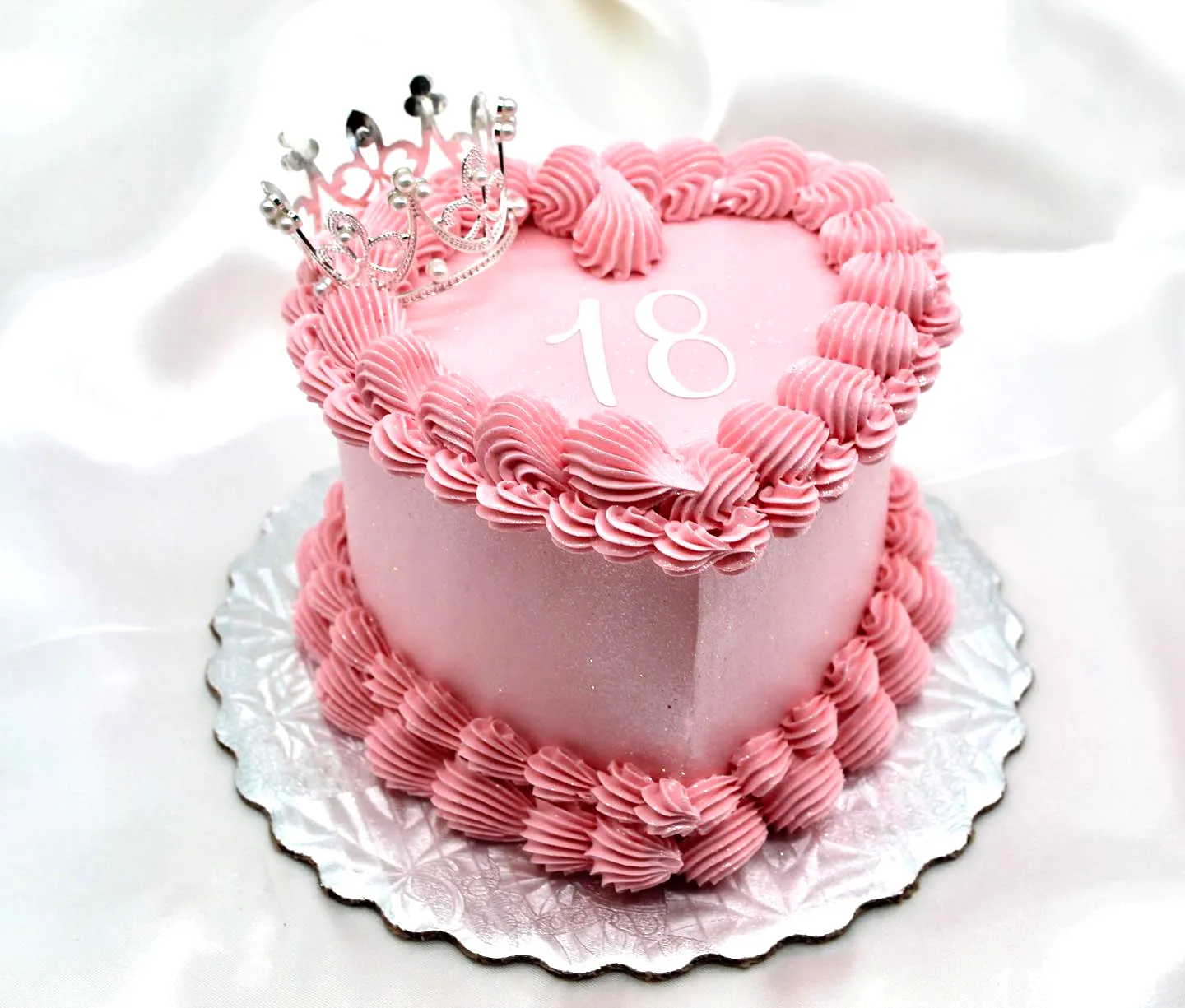 Cute heart-shaped 18th birthday cake with pink buttercream and silver crown