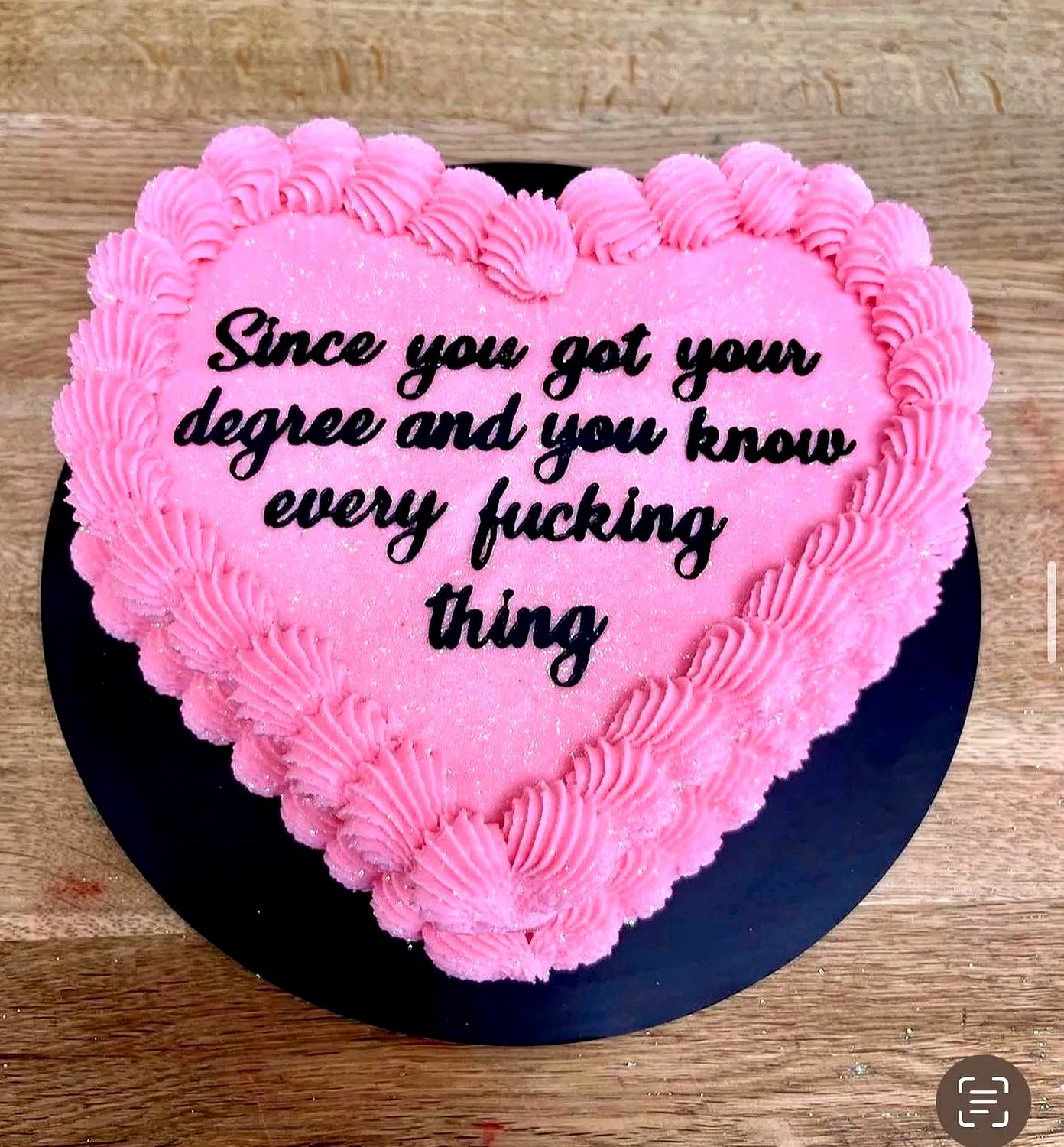 Cute heart-shaped simple graduation cake with vibrant pink frosting and sparkle
