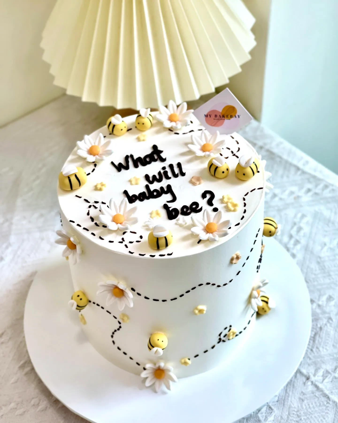 Cute nature-inspired gender reveal cake with cheerful bees and playful flowers