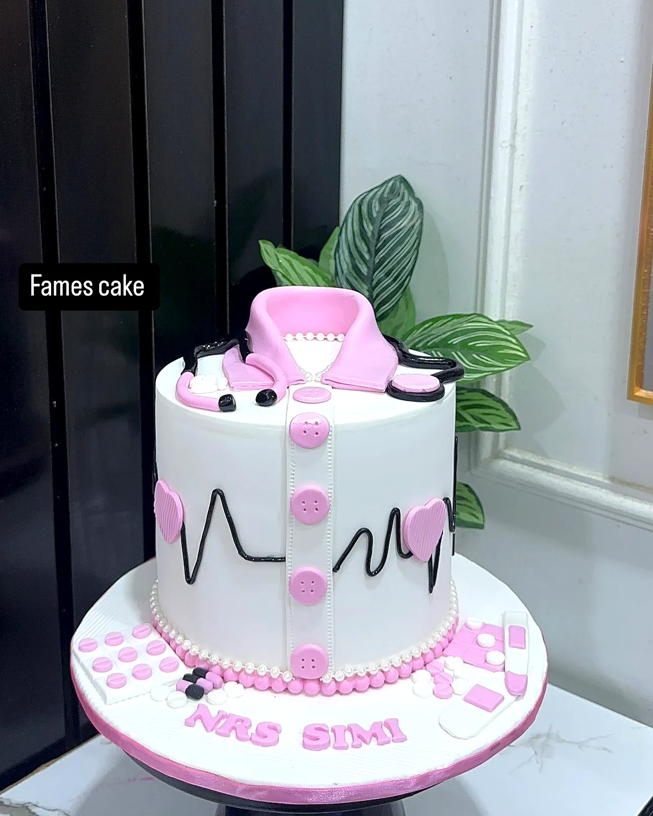 Cute nurse graduation cake with pink and black medical theme decorations