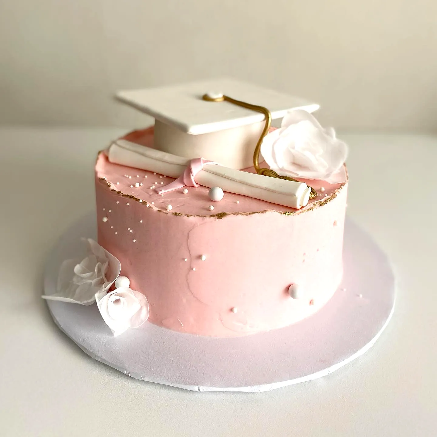 Cute pink graduation cake design with elegant decorations and smooth finish