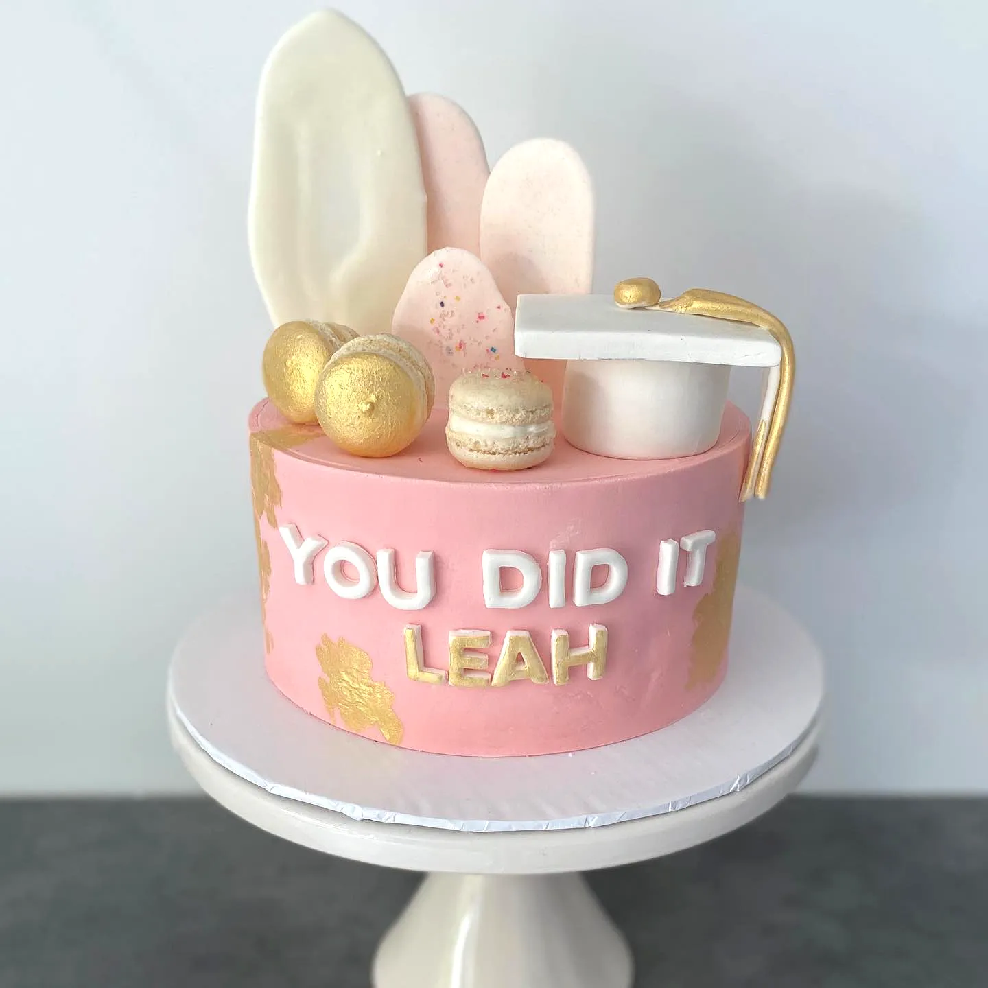 Cute pink graduation cake with elegant gold accents and celebratory decor