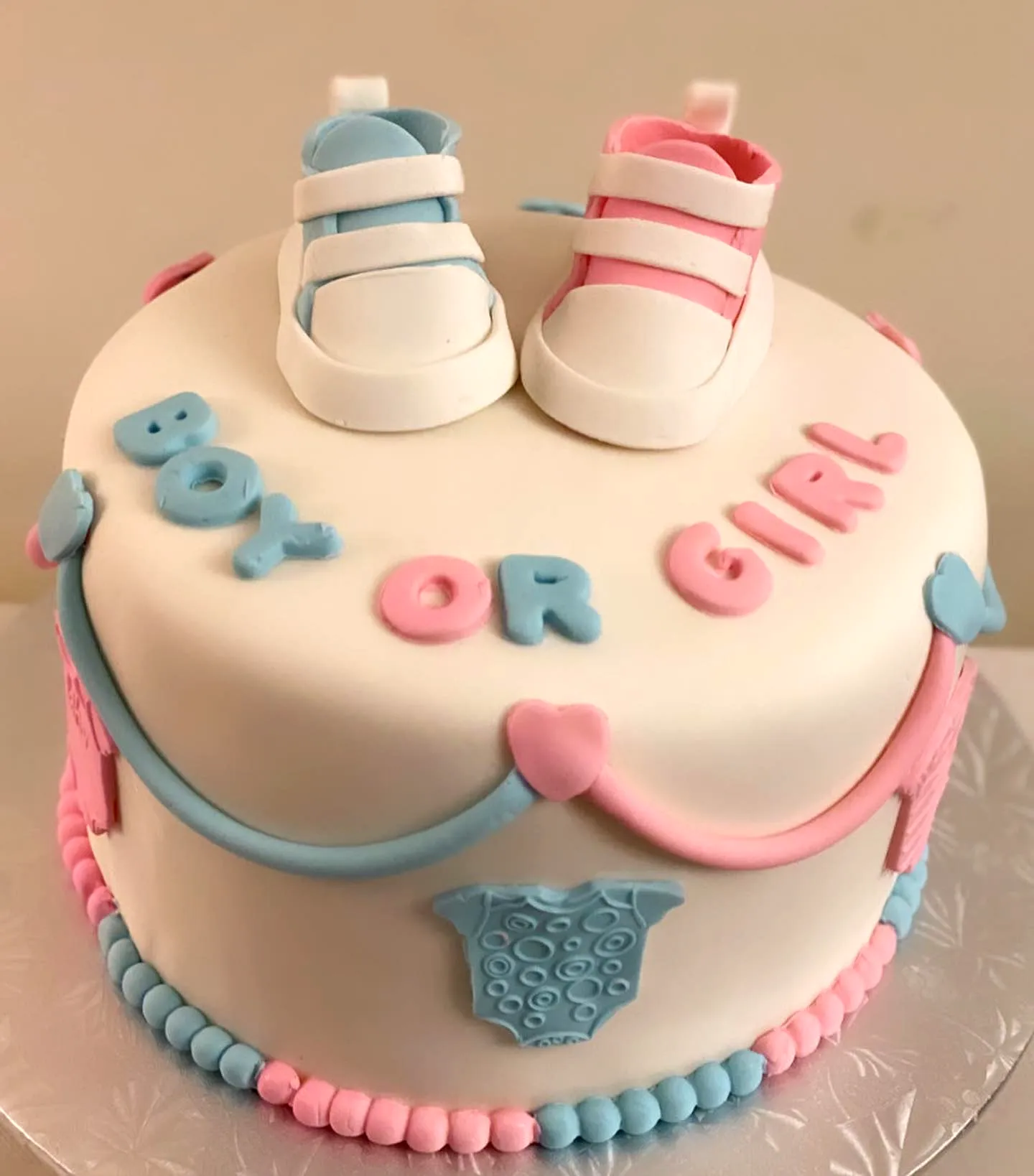 Cute Two-Tiered Gender Reveal Cake with Pastel Accents and Playful Decor