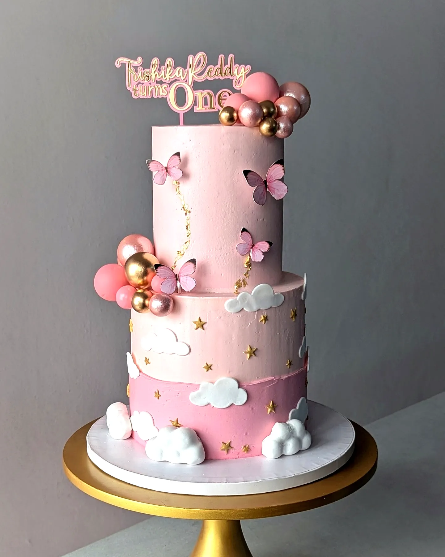 Cute two-tiered pink birthday cake for a delightful 1st birthday celebration