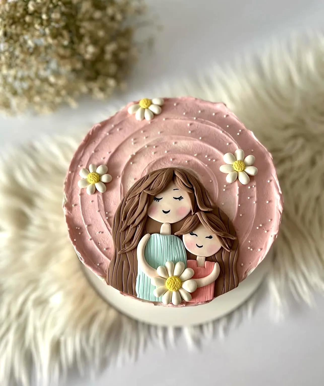 Cute whimsical birthday cake for mom with pink frosting and fondant figures
