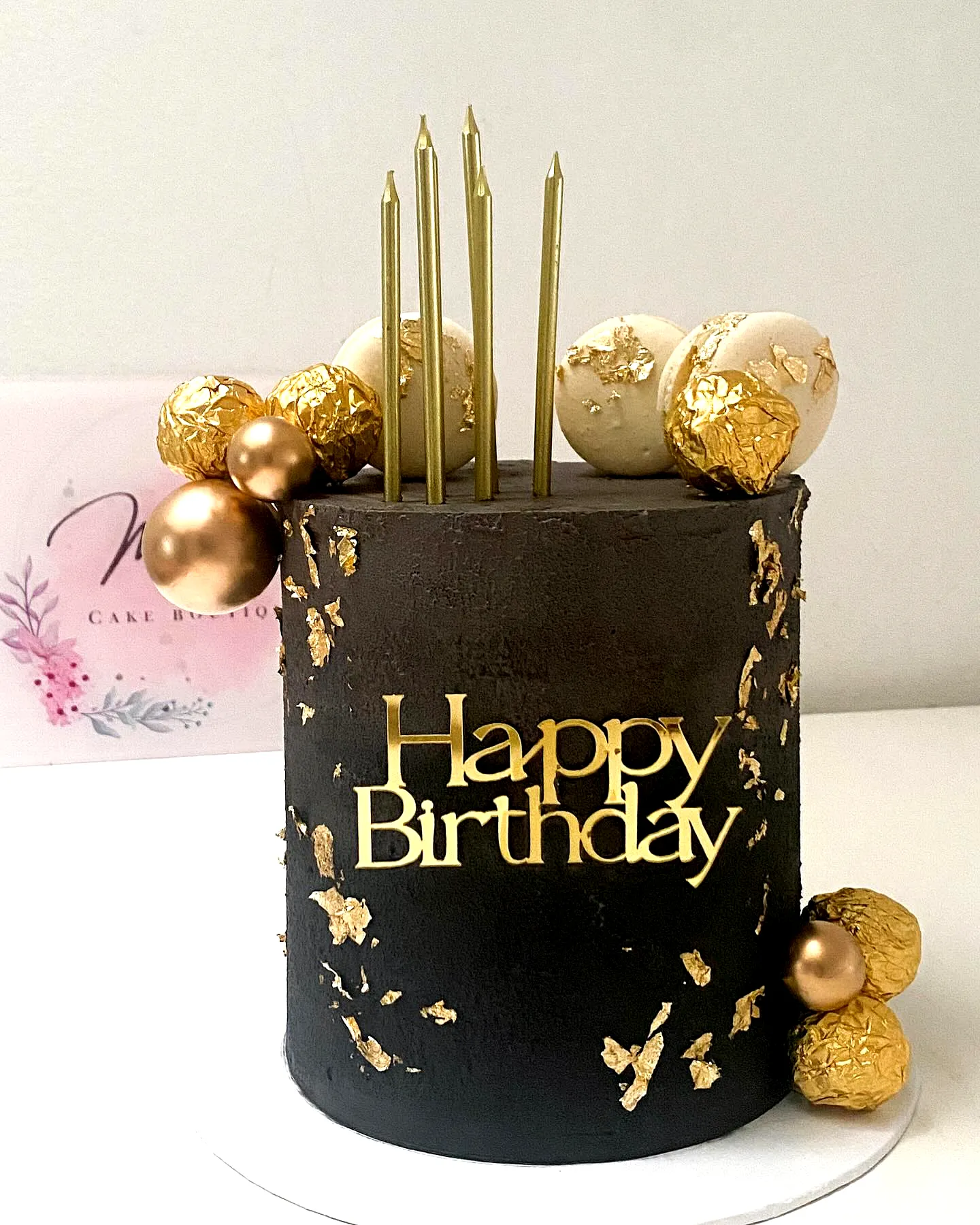 Elegant black birthday cake design with gold accents and festive decorations