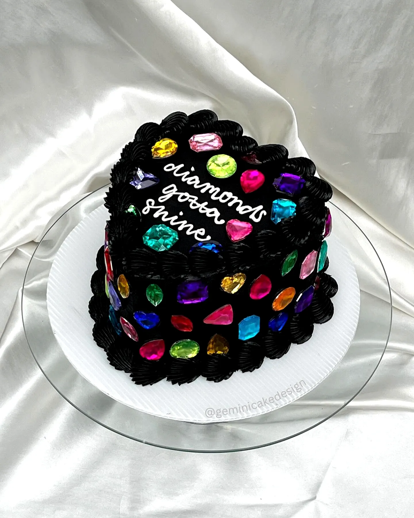 Elegant black Taylor Swift birthday cake with vibrant gem decorations