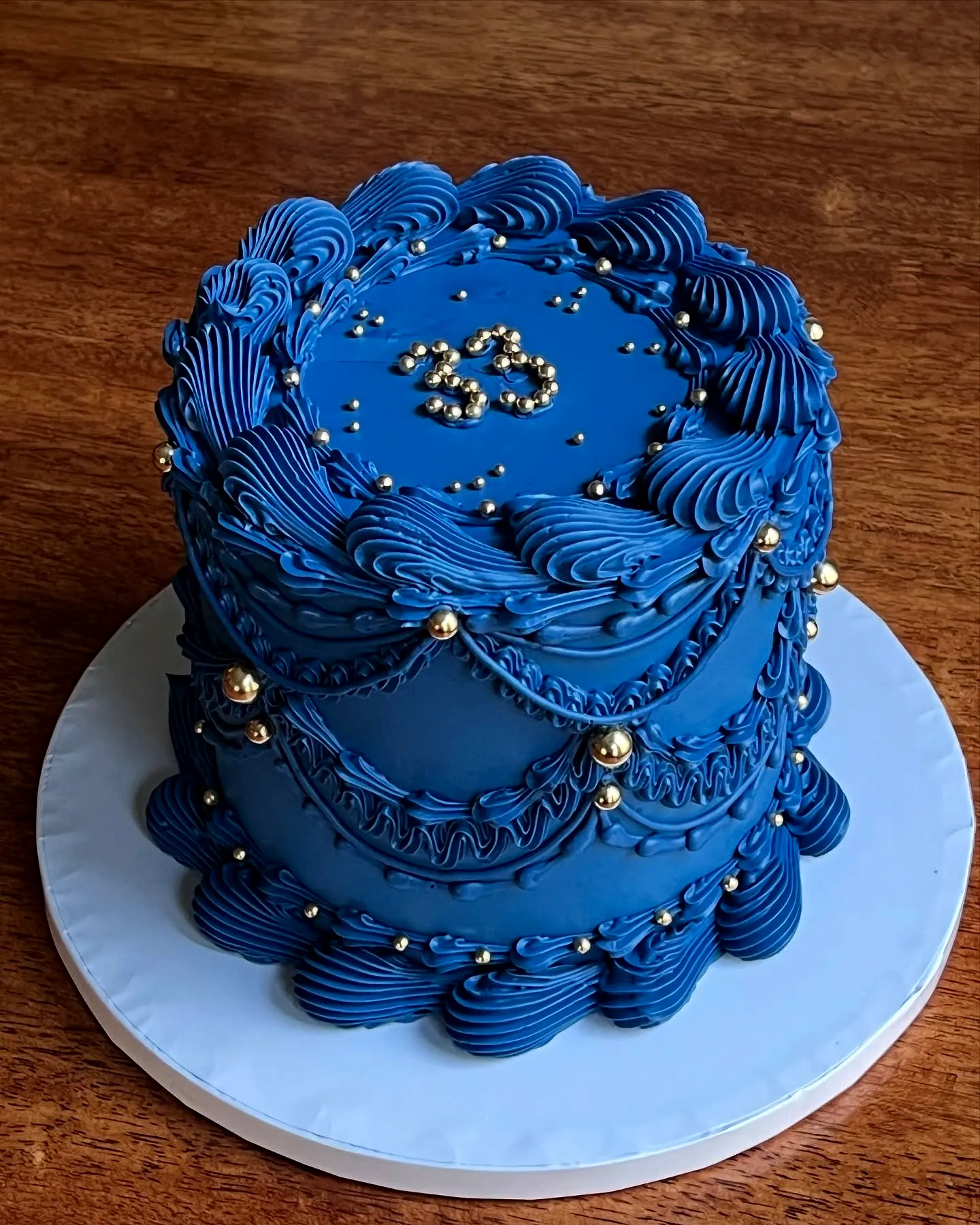 Elegant blue birthday cake design with smooth buttercream and gold accents