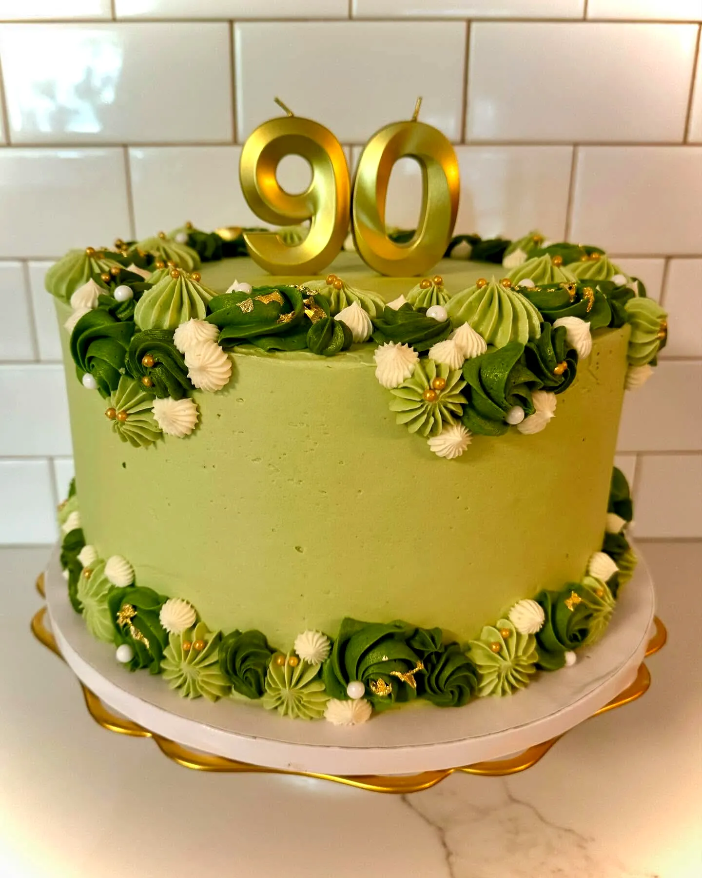 Elegant buttercream 90th birthday cake with golden numerals and rosettes