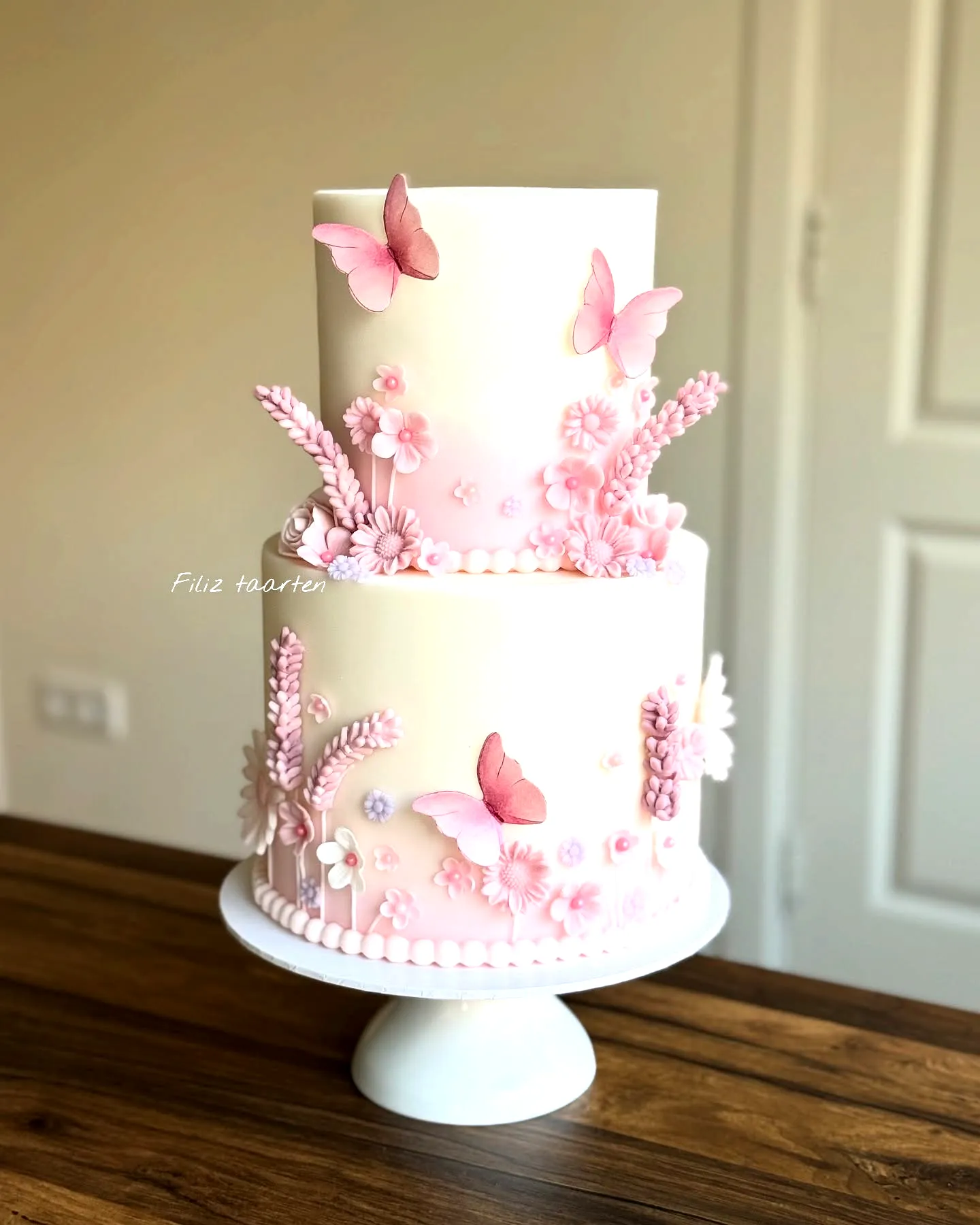 Elegant butterfly birthday cake design with soft pink hues and sugar decorations