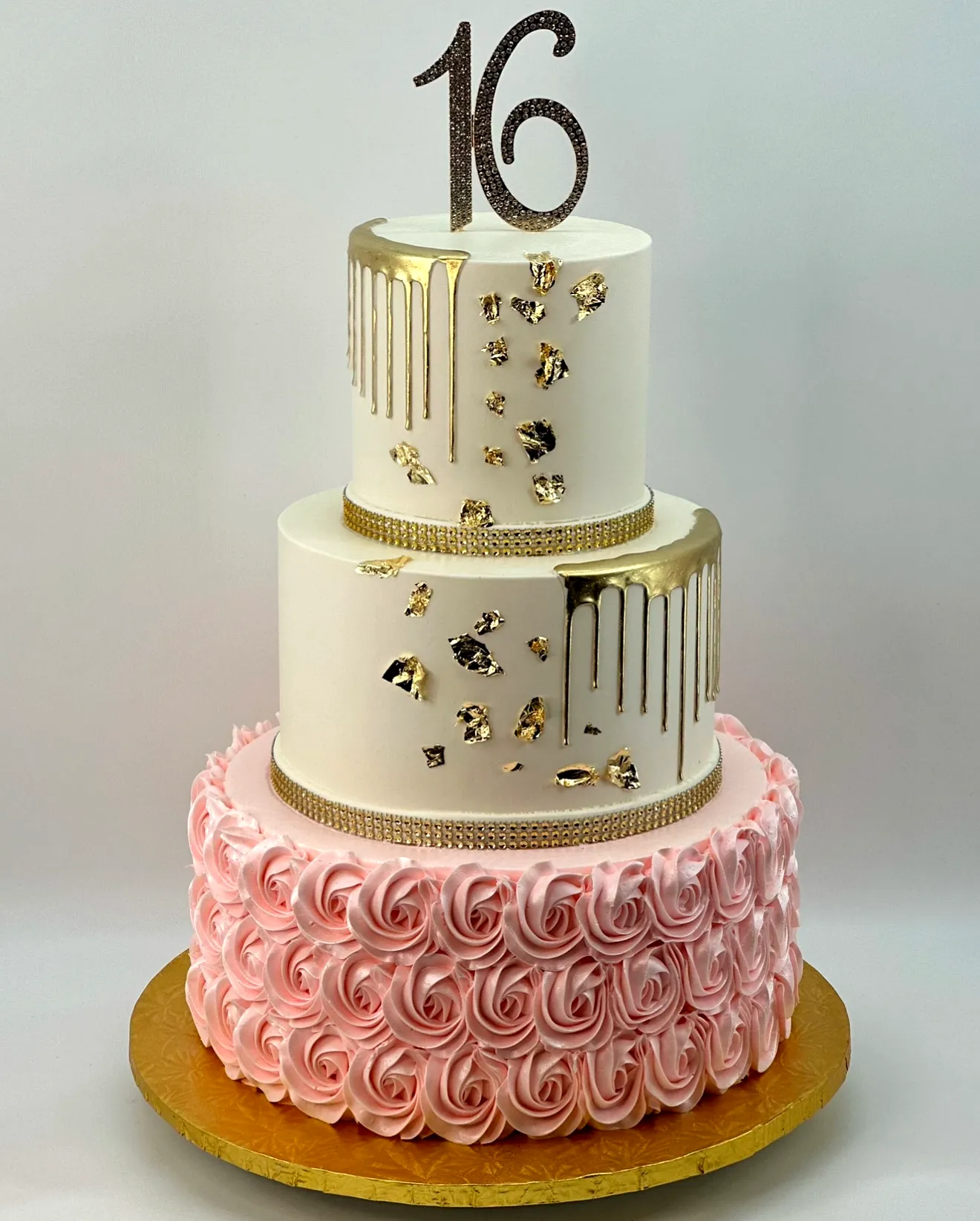 Elegant golden birthday cake design with pink rosettes and gold accents