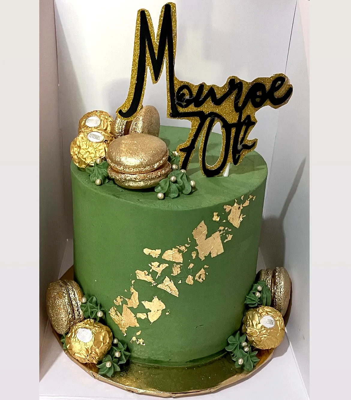 Elegant green 70th birthday cake design with gold accents and macarons