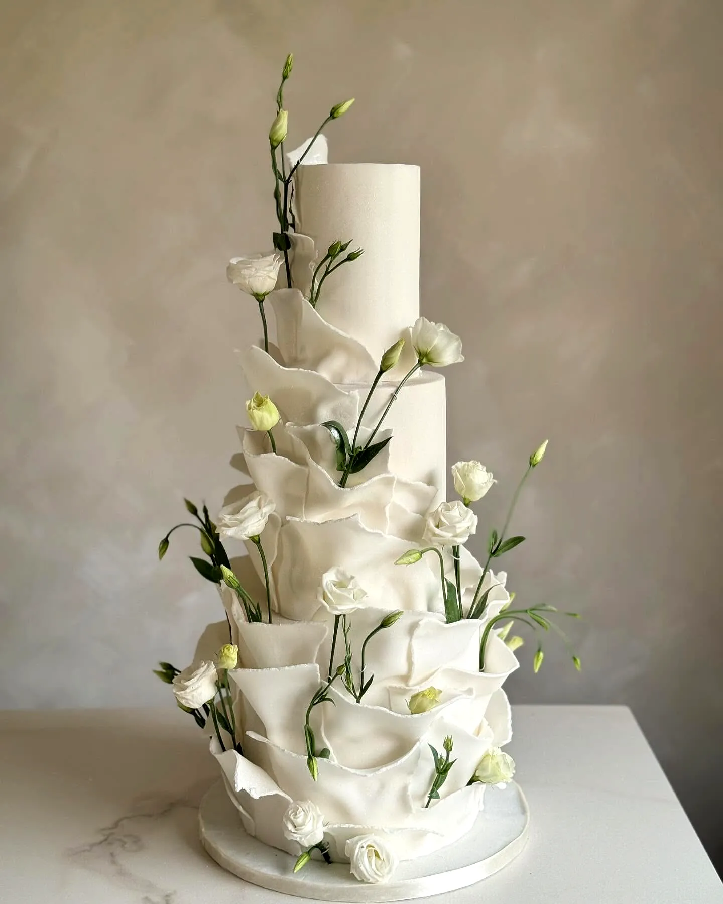 Elegant multi-tiered wedding shower cake with delicate ruffles and fresh flowers