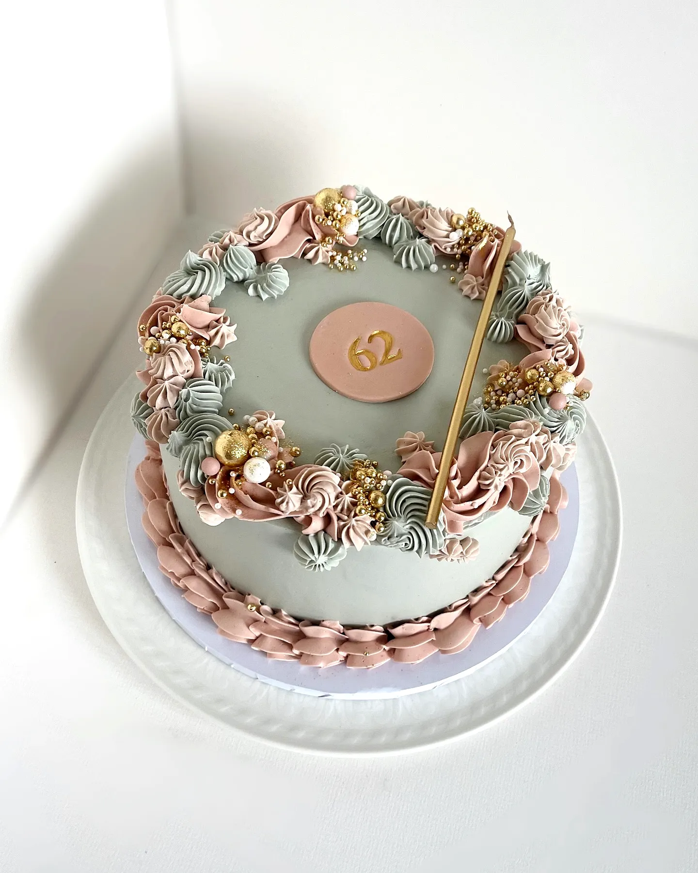 Elegant pastel green 60th birthday cake with floral accents and gold decor