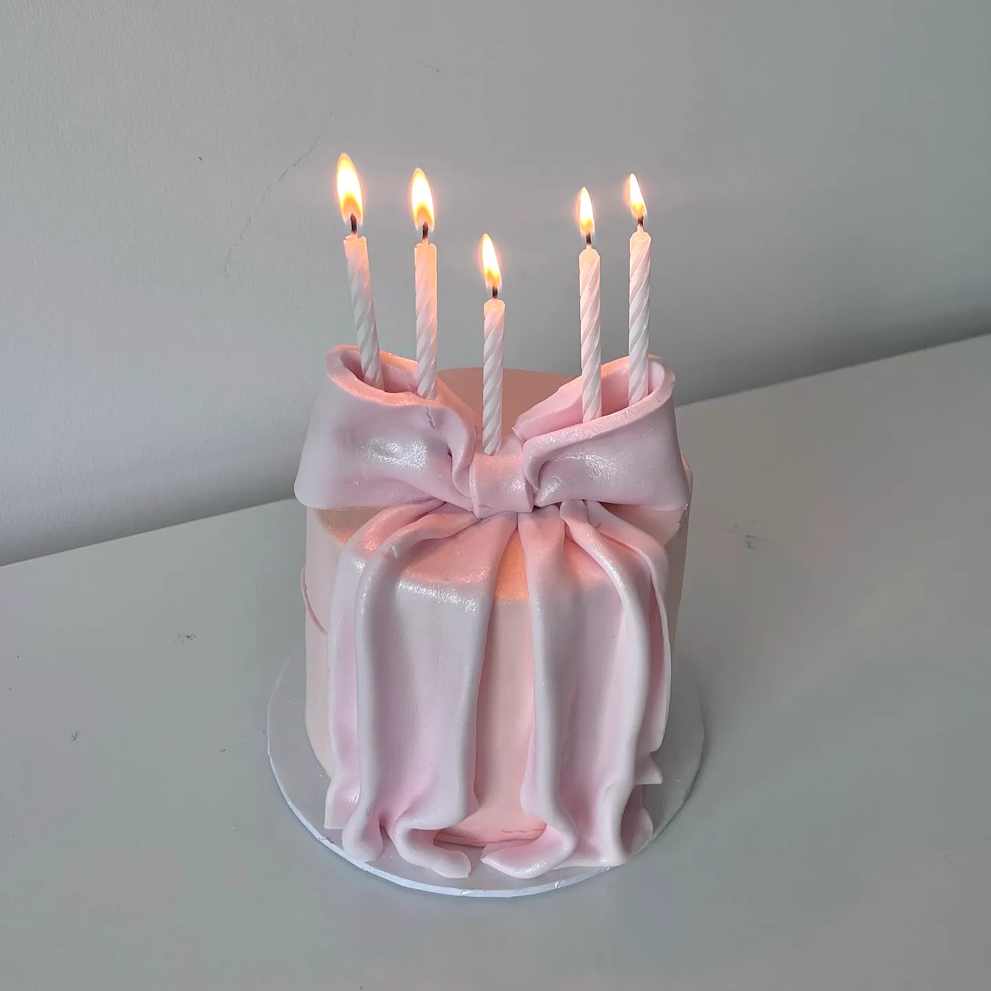 Elegant pink birthday cake design with fondant texture and festive candles