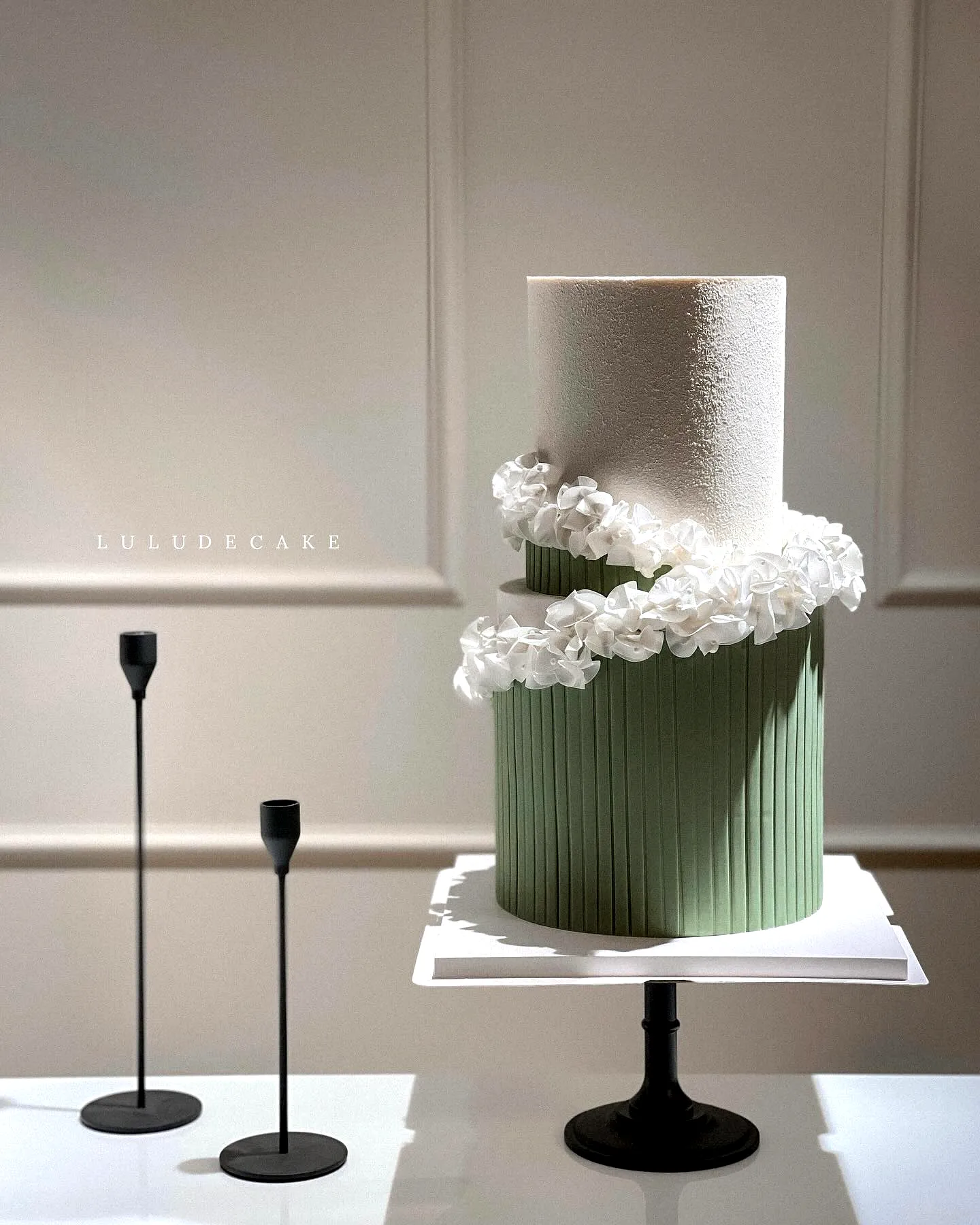 Elegant two tier wedding cake design in muted green with floral accents
