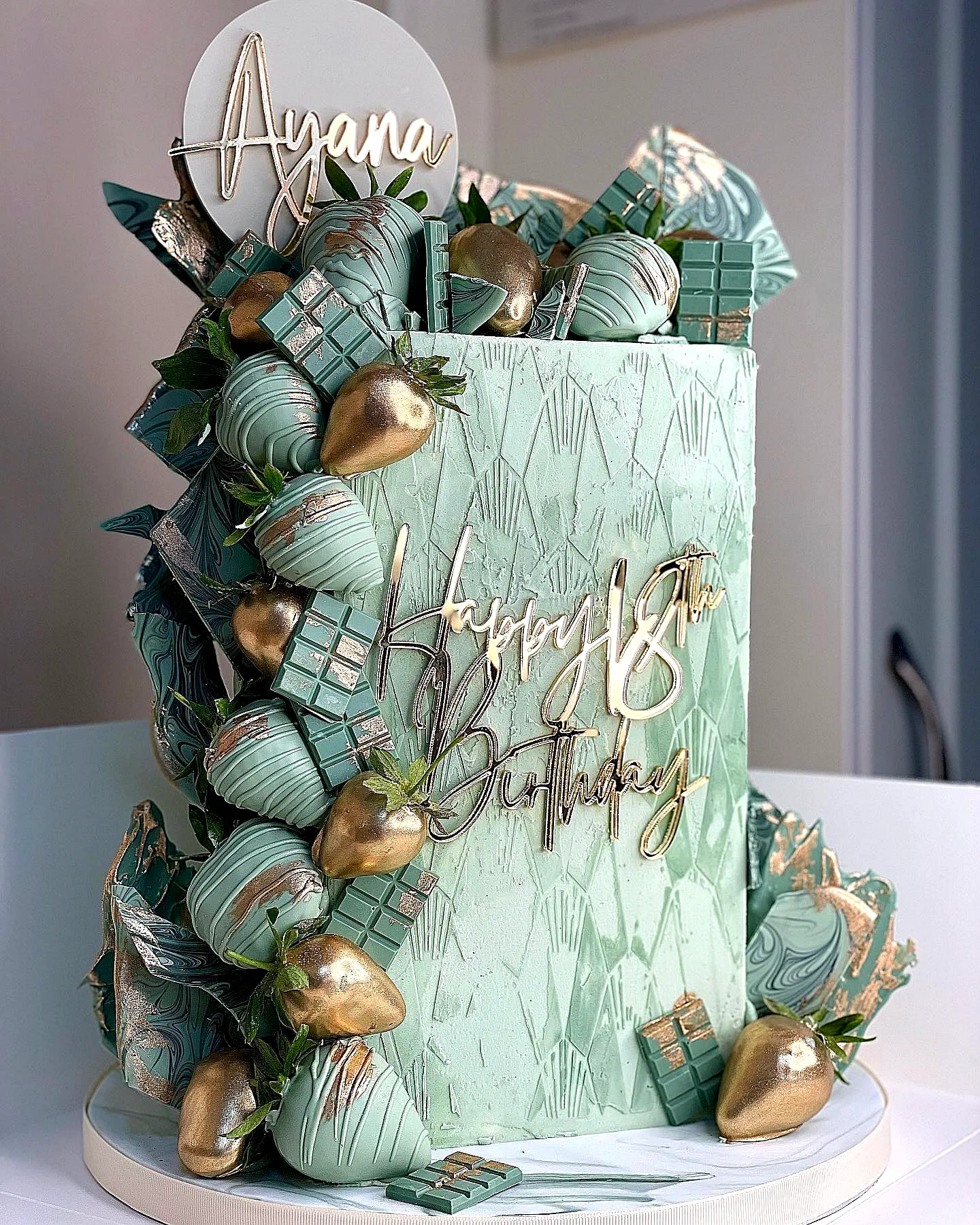 Elegant two-tiered birthday cake design in mint green with gold accents