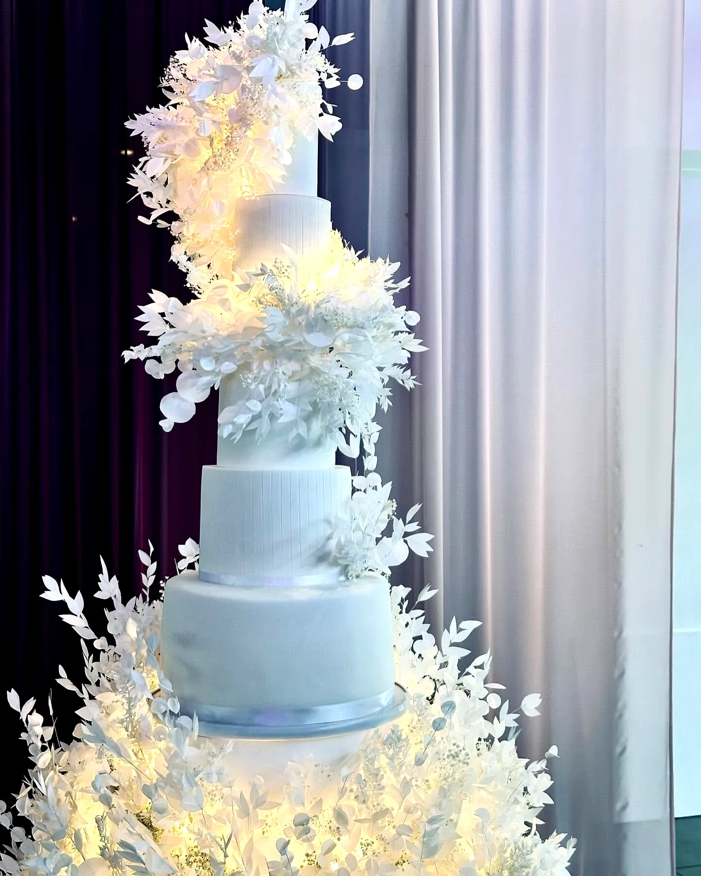 Elegant wedding cake design featuring modern ribbed patterns and floral decor