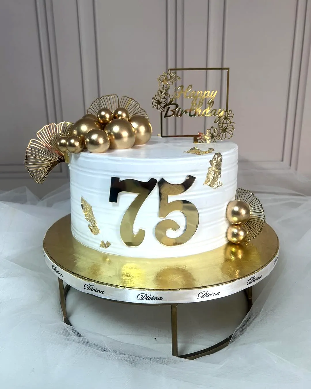 Elegant white 75th birthday cake with gold accents and delicate decorations