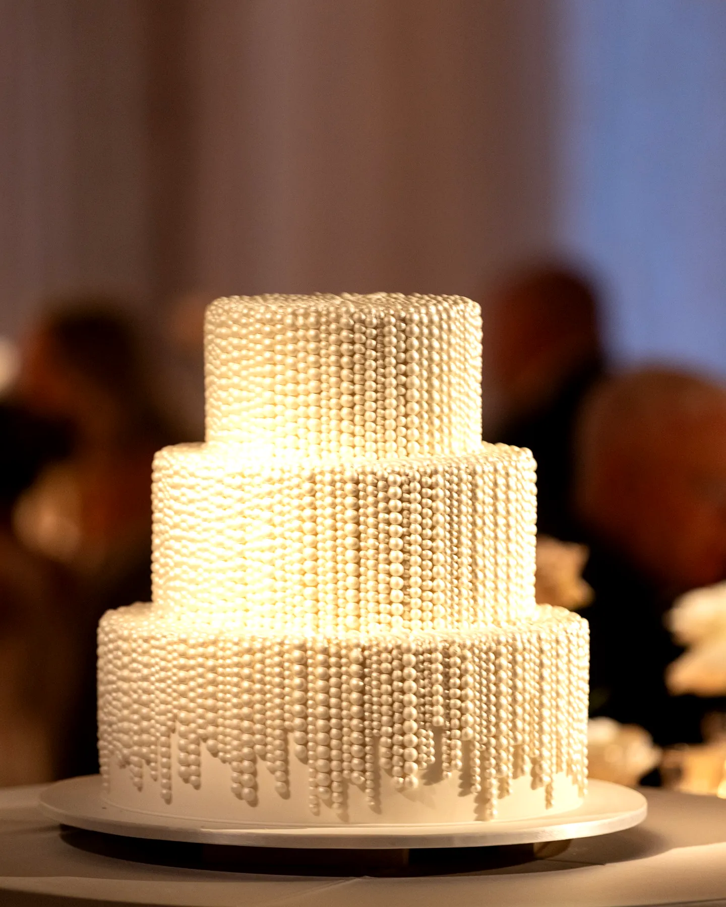 Elegant white wedding cake design with modern textures and pearl embellishments