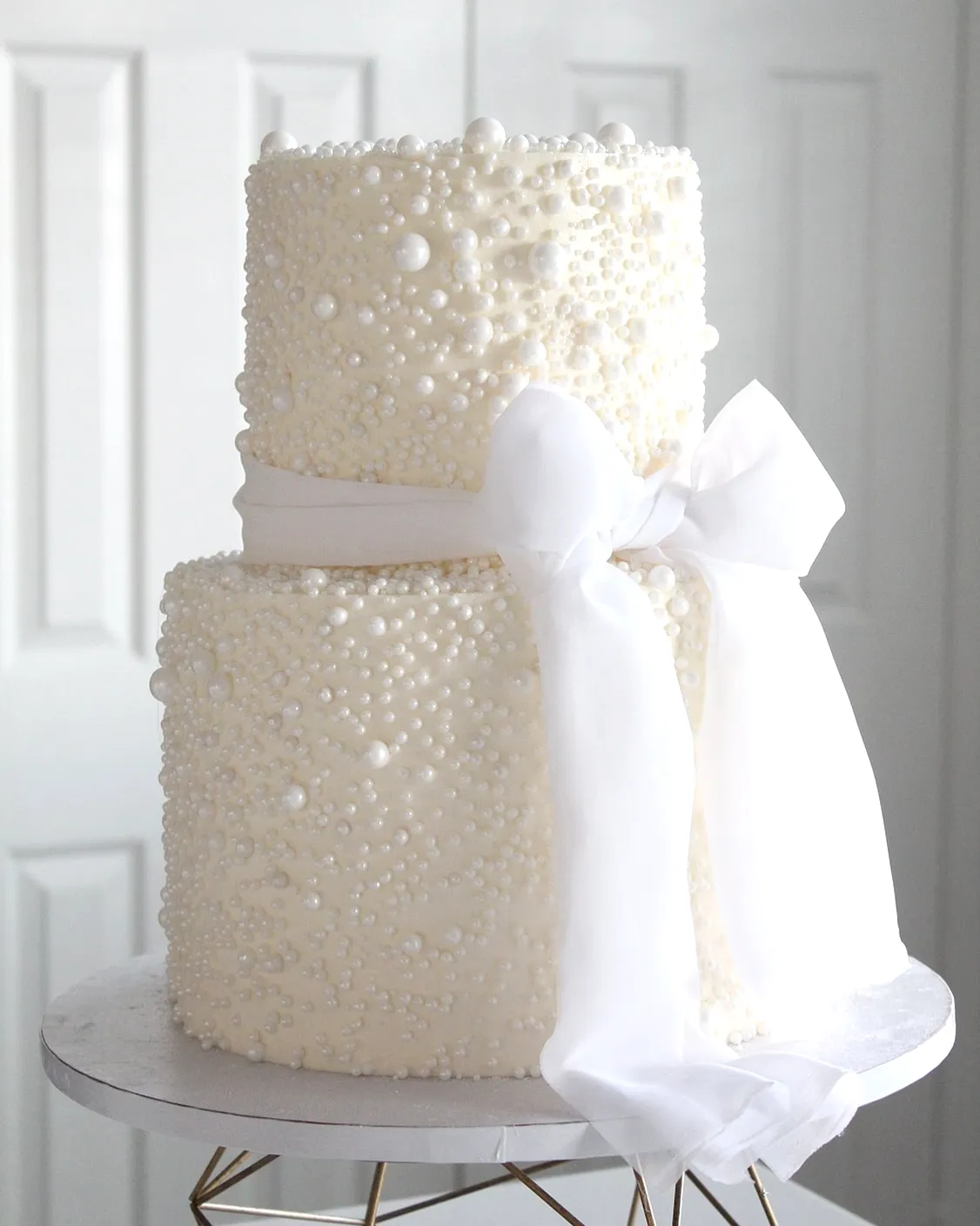 Elegant white wedding cake design with textured surface and pearls