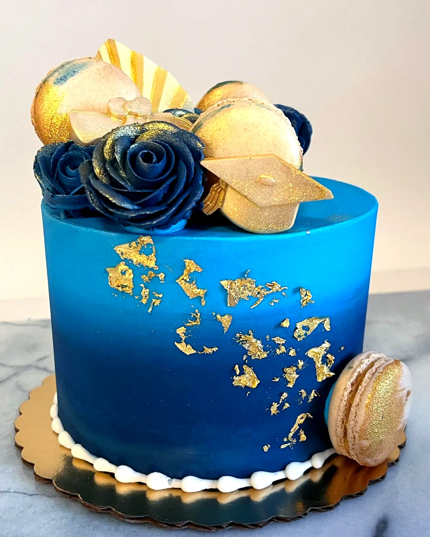Lovely blue and gold graduation cake design with ombre frosting and elegant accents