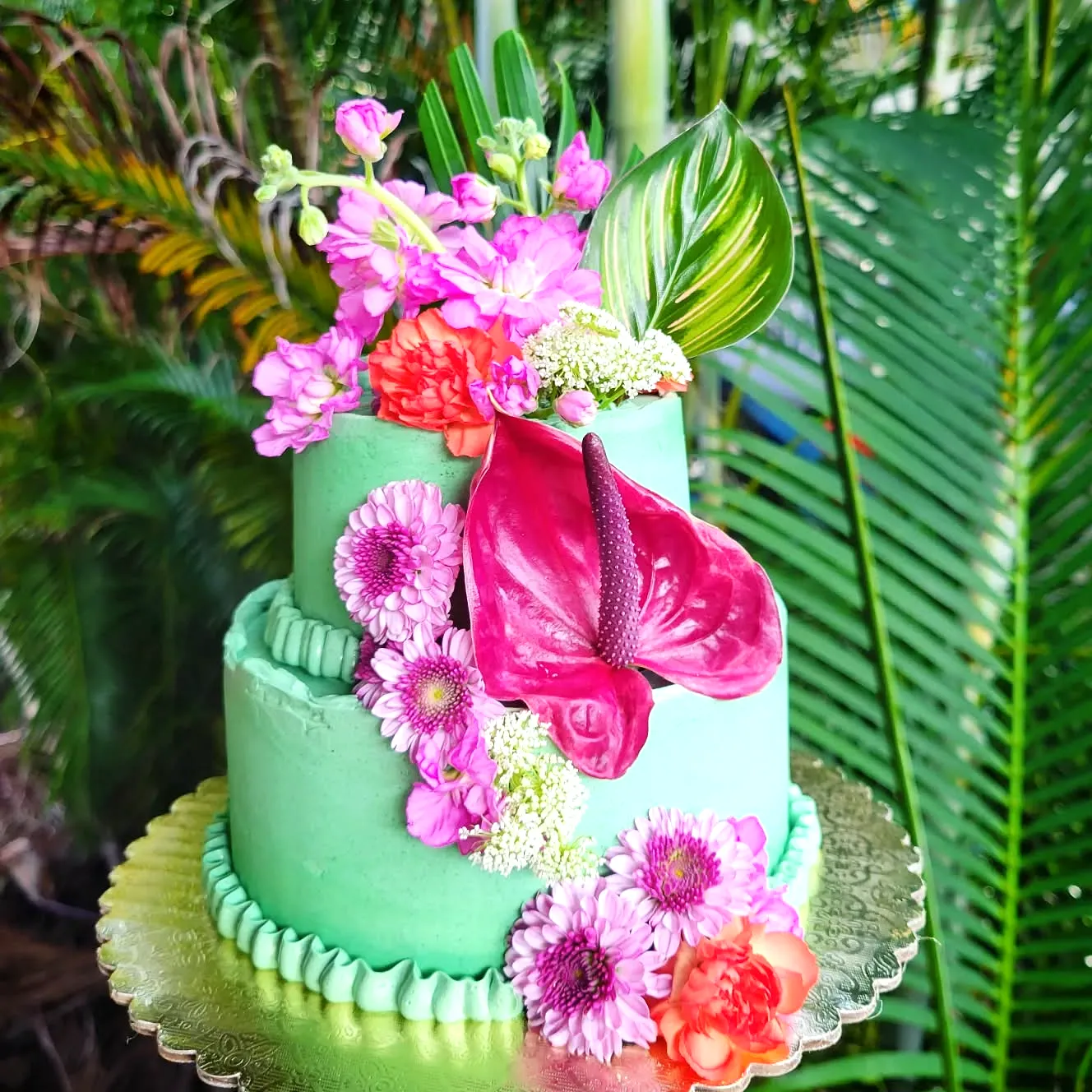 Lovely contemporary wedding cake in mint green with vibrant tropical flowers
