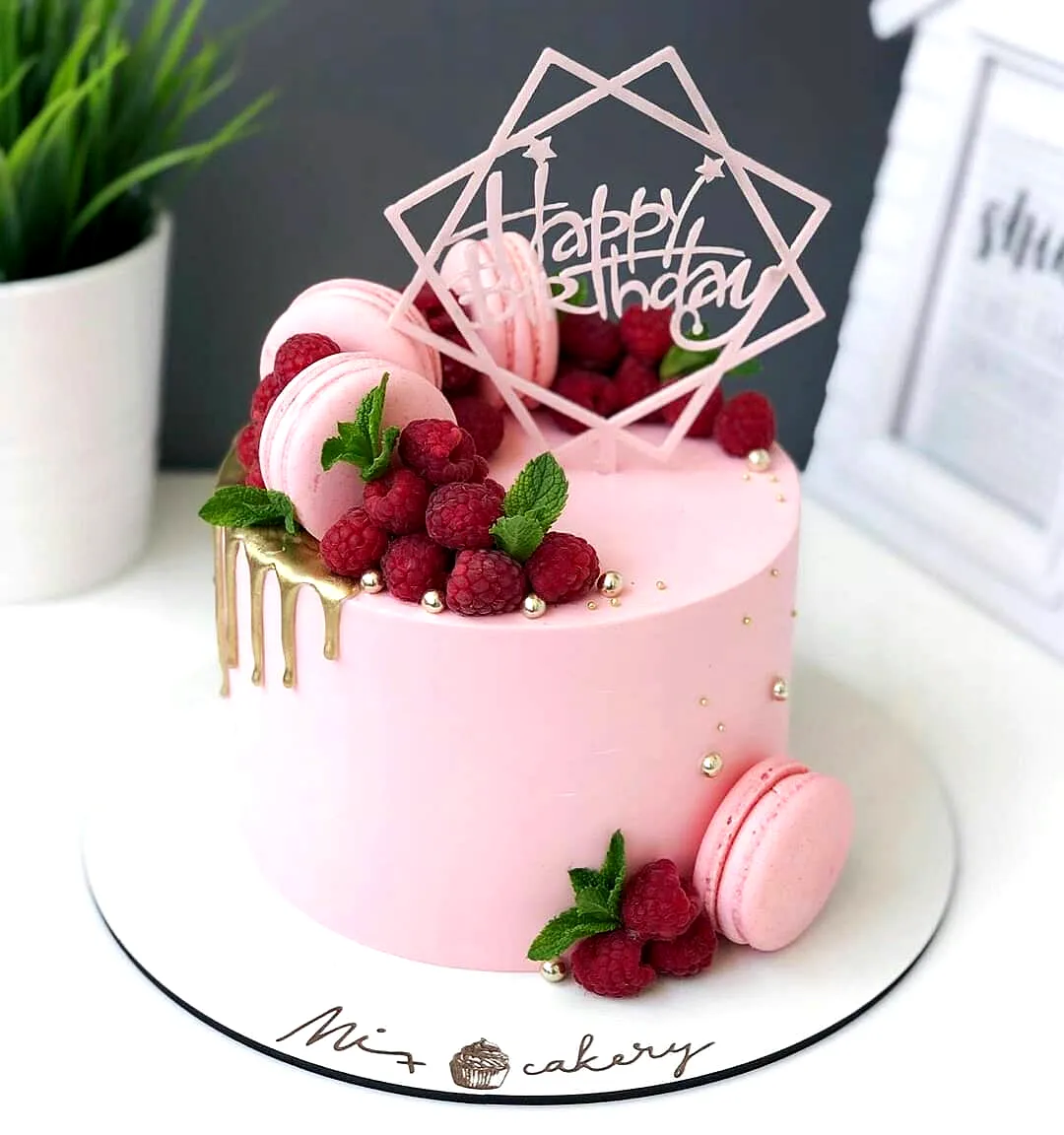 Lovely pink birthday cake design with fresh raspberries and macarons